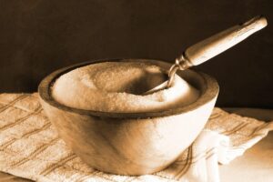 wooden bowl, vintage metal scoop, sugar scoop, wooden handle, white granulated sugar, dishcloth, table top image, sepia